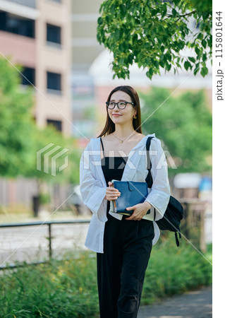 手帳を持って歩く若い女性 115801644