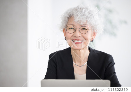 パソコンの考えるグレイヘアの笑顔の表情の女性の取締役や社長、会長など役員のエクゼクティブなイメージ  115802859