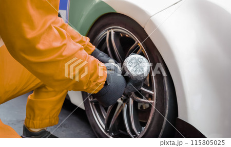 Auto mechanic changing car wheel in garage. 115805025