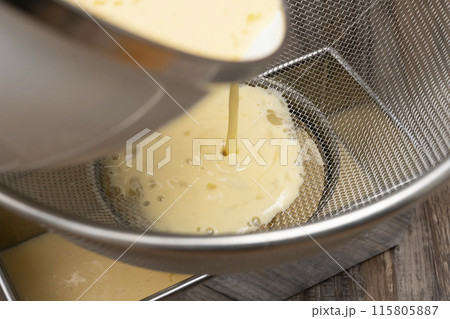 プリンを作る工程　卵液を笊で漉して型に入れる 115805887