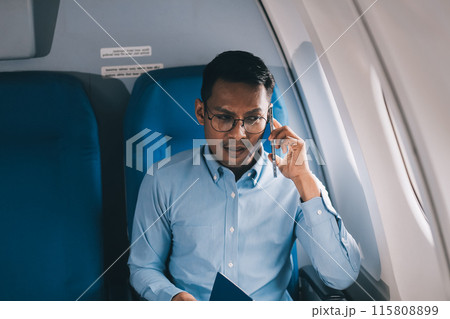 Attractive Asian male passenger of airplane sitting in comfortable seat while working laptop and tablet with mock up area using wireless connection. Travel in style, work with grace. 115808899