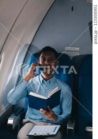 Attractive Asian male passenger of airplane sitting in comfortable seat while working laptop and tablet with mock up area using wireless connection. Travel in style, work with grace. Attractive Asian male passenger of airplane sitting in comfortable seat while working laptop and tablet with mock up area using wireless connection. Travel in style, work with grace. 115808901