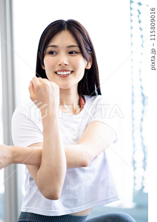 ストレッチをする女性のポートレート （白い半袖フィットネスウェアと黒髪ロングヘア） 115809016