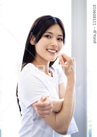 ストレッチをする女性のポートレート （白い半袖フィットネスウェアと黒髪ロングヘア） 115809018