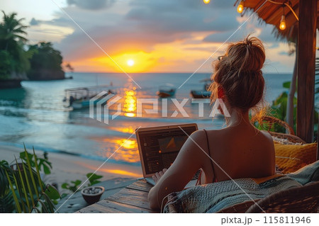 Female freelancer with laptop on the beach during sunset. Place of work of a hermit freelancer. 115811946