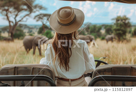 Woman Wearing a Hat Observing Elephants in African Savanna Woman Wearing a Hat Observing Elephants in African Savanna 115812897