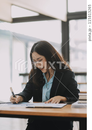 Young beautiful woman typing on tablet and laptop while sitting at the working wooden table modern office 115813265