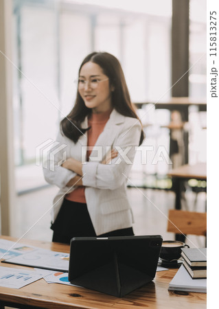 Happy young asian businesswoman sitting on her workplace in the office. Young woman working at laptop in the office. Happy young asian businesswoman sitting on her workplace in the office. Young woman working at laptop in the office. 115813275