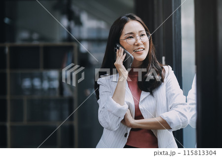 Portrait of a happy Asian businesswoman using mobile phone indoor, Asian businesswoman working in modern office. 115813304
