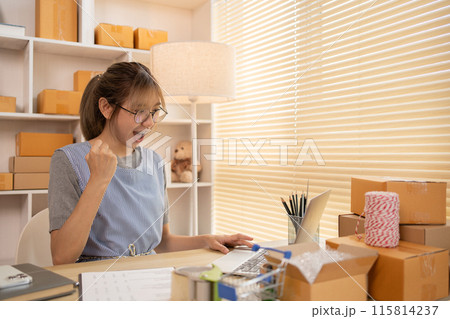 Sell products online, Happy Woman Celebrating Order from Internet Customer: New Business Style, Online Selling, Young Entrepreneur's Success: Work-from-Home SME Owner Thrives in Online Sales. 115814237