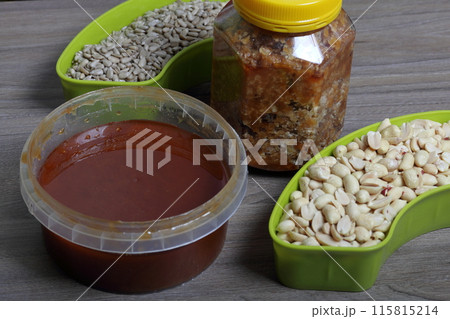Honey in a container. Next to separate containers of peanuts and sunflower seeds. Ingredients for making halva. Honey in a container. Next to separate containers of peanuts and sunflower seeds. Ingredients for making halva. 115815214