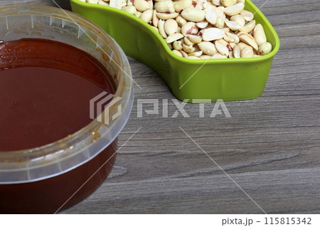 Honey in a container. Next to separate containers of peanuts and sunflower seeds. Ingredients for making halva. 115815342