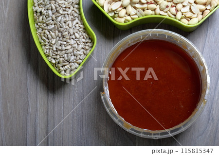 Honey in a container. Next to separate containers of peanuts and sunflower seeds. Ingredients for making halva. 115815347