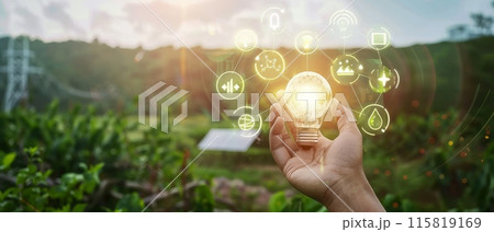 Hand holding light bulb with green energy icons, sustainable power concept in a scenic nature background 115819169