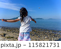 海岸で海に向かって小石を投げる女の子、後ろ姿 115821731
