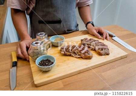 Chef at the kitchen preparing beef steaks on the home electric grill 115822615