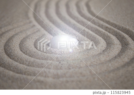 Shining Zen stone in the middle of curve lines on sand 115823945
