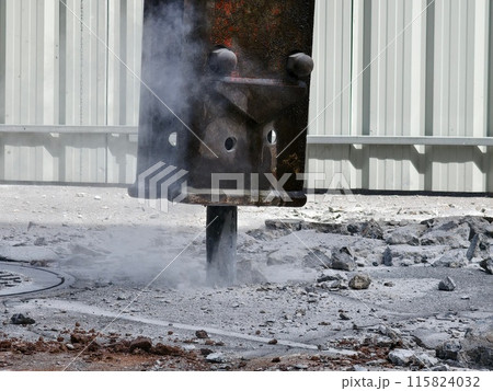 A hydraulic hammer breaking concrete at a construction site 115824032