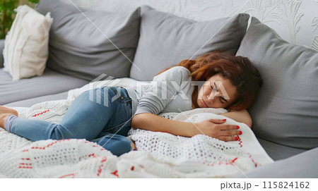 Woman with period or abdominal pain on a sofa 115824162