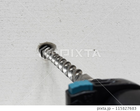 Work of a jackhammer. Drilling hole in concrete wall. 115827683