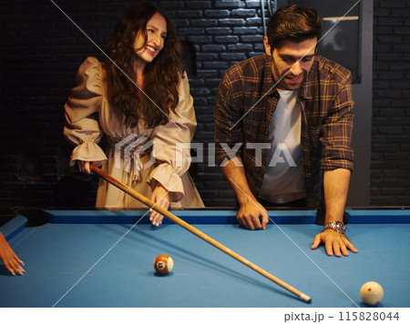 Man teaching his girl   to play pool or billiards . Pleasant pastime, family rest, entertainment, holiday. 115828044