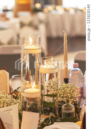 Soft lit candles in glass vases with flowers 115828140