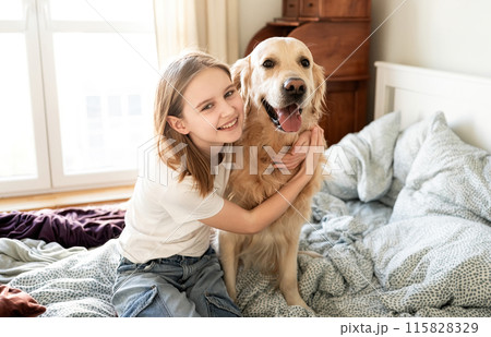 Joyful Little Girl Hugging Golden Retriever Dog And Looking Into The Cameara Joyful Little Girl Hugging Golden Retriever Dog And Looking Into The Cameara 115828329