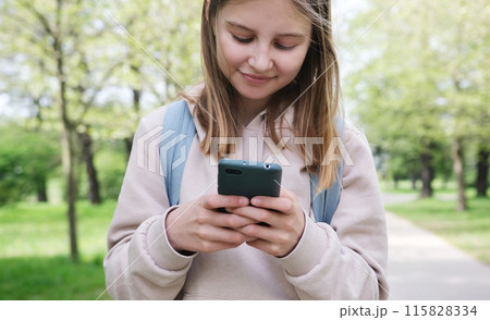 Adorable Small Girl Using A Smartphone In The Park Adorable Small Girl Using A Smartphone In The Park 115828334