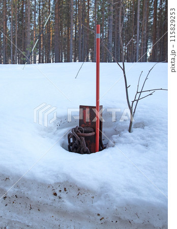 Chain and red pole at the side of a forest road 115829253