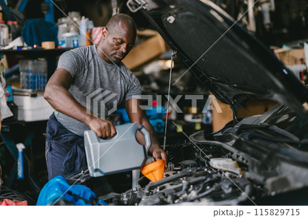 Garage Mechanic Worker African Black male professional working car auto service checking engine oil change. Garage Mechanic Worker African Black male professional working car auto service checking engine oil change. 115829715