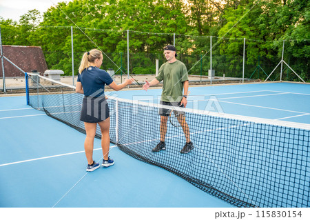 Professional tennis players shaking hands at the end of a tennis game on outside court Professional tennis players shaking hands at the end of a tennis game on outside court 115830154