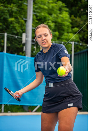 Professional female tennis player serving the tennis ball during playing on outside court 115830164