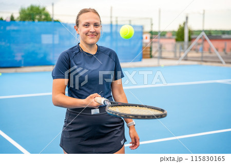 Professional female tennis player posing with the tennis racket and ball on outside court 115830165