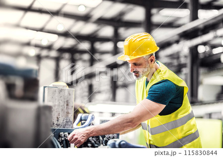 Warehouse employee in warehouse. Male worker in reflective clothing in modern industrial factory, heavy industry, manufactrury. 115830844