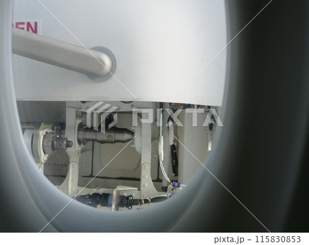 Through aircraft window on passenger seat details of door visible. Perfect for travel and aviation content. Window view showing aircraft interior and door perspective through window during flight. 115830853