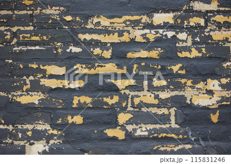 Old black brick wall with peeling paint 115831246