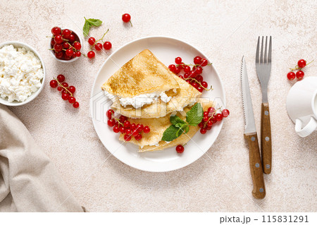 Crepes or thin pancakes with cheese cottage or curd and fresh red currant berries, top view Crepes or thin pancakes with cheese cottage or curd and fresh red currant berries, top view 115831291
