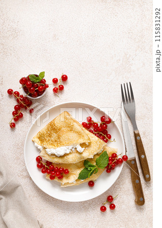 Crepes or thin pancakes with cheese cottage or curd and fresh red currant berries, top view Crepes or thin pancakes with cheese cottage or curd and fresh red currant berries, top view 115831292