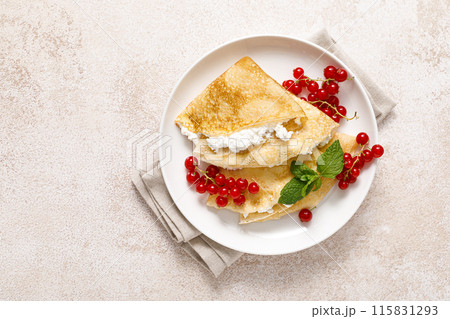 Crepes or thin pancakes with cheese cottage or curd and fresh red currant berries, top view 115831293