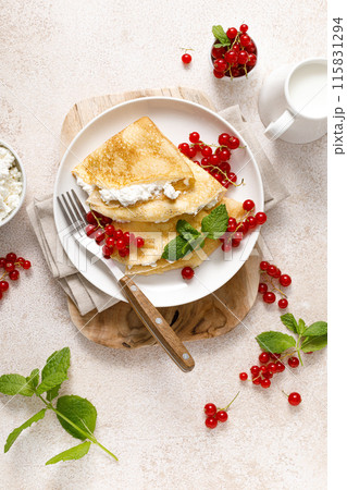 Crepes or thin pancakes with cheese cottage or curd and fresh red currant berries, top view Crepes or thin pancakes with cheese cottage or curd and fresh red currant berries, top view 115831294