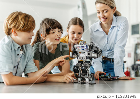 Children learning robotics in Elementary school. Young students building robot in after school robotics club. Field trip to real robotics laboratory. 115831949