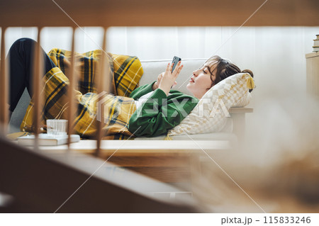 自宅のソファーでスマホを見る女性 自宅のソファーでスマホを見る女性 115833246