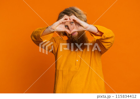 Smiling lovely man makes heart gesture demonstrates love sign expresses good feelings and sympathy Smiling lovely man makes heart gesture demonstrates love sign expresses good feelings and sympathy 115834412