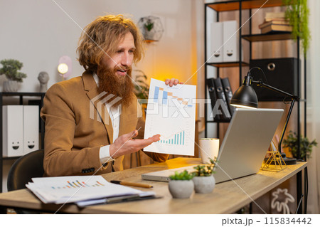 Businessman working on laptop at home office desk talks on online communication webcam video call 115834442