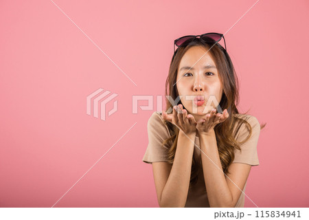 Asian happy portrait beautiful cute young woman teen standing blowing kiss air something on palm hands expresses her love looking to camera studio shot isolated on pink background with copy space 115834941
