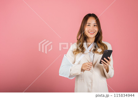 Woman confident smiling broken arm after accident and wear arm splint for treatment and hold smartphone, happy Asian female sling supported hand isolated on pink background, social media, copy space Woman confident smiling broken arm after accident and wear arm splint for treatment and hold smartphone, happy Asian female sling supported hand isolated on pink background, social media, copy space 115834944