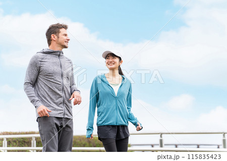 公園で景色を見ながらウォーキングするスポーツウェアを着た男女（夫婦・カップル） 115835423