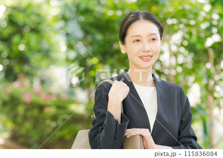 新緑の中でスーツを着て微笑む女性 115836084