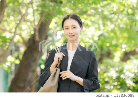 新緑の中でスーツを着て微笑む女性 115836089