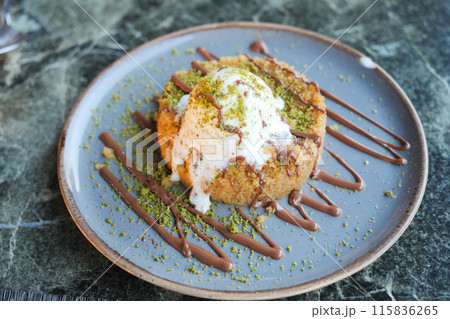 Gourmet dessert with pistachio garnish and chocolate drizzle beautifully presented on a plate Gourmet dessert with pistachio garnish and chocolate drizzle beautifully presented on a plate 115836265